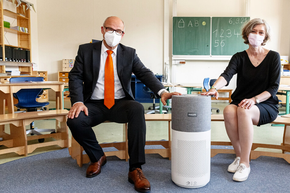 Schulsenator Ties Rabe (SPD) sitzt mit Marion Bottek, Schulleiterin der Grundschule Richardstraße, neben dem ersten mobilen Luftfiltergerät gegen Corona-Viren für eine Hamburger Schule.