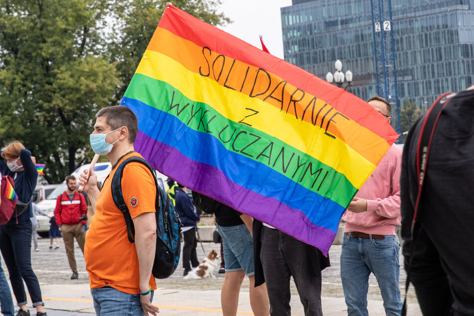 Demonstranten der Bewegung "No more" halten während eines Protestes in Polen 2020 eine Regenbogenfahne mit der Aufschrift "Solidarität mit den Ausgeschlossenen" hoch.