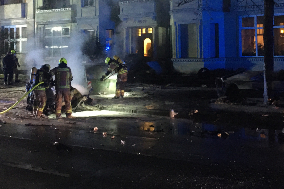 Feuerwehrkräfte löschen das brennende Auto.