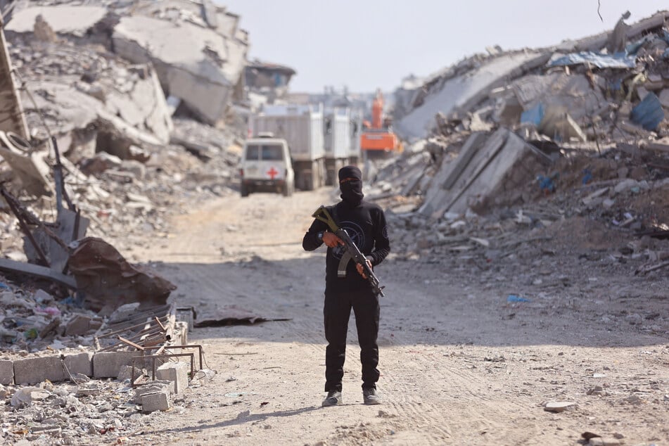 Ein Hamas-Terrorist steht inmitten eines zerstörten Straßenzuges.