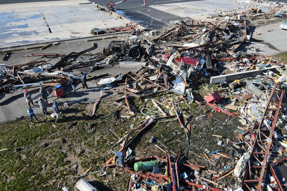 People search for salvageable parts near destroyed aircraft, hangar pieces, and other debris at Robinson Municipal Airport, two days after a tornado hit Palestine, Illinois.