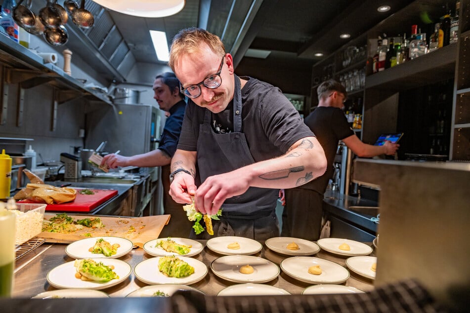 Koch Manuel Neuber richtet die Teller für die Eröffnungsgäste an.