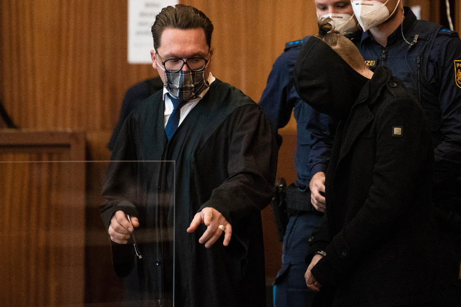 Der wegen sexuellen Missbrauchs von Kindern Angeklagte (vorne) wird von zwei Polizisten in den Saal der Stadthalle Schweinfurt geführt (Archivbild).