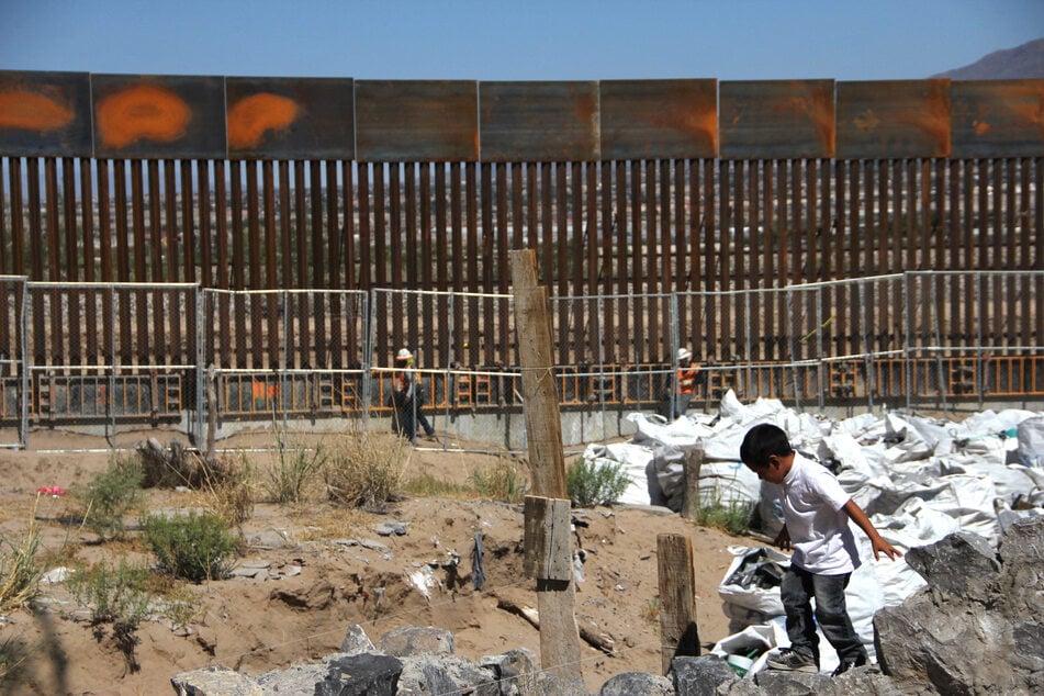 A child plays in front of a section of the US-Mexico border wall, which is expected to be completed by late 2027.