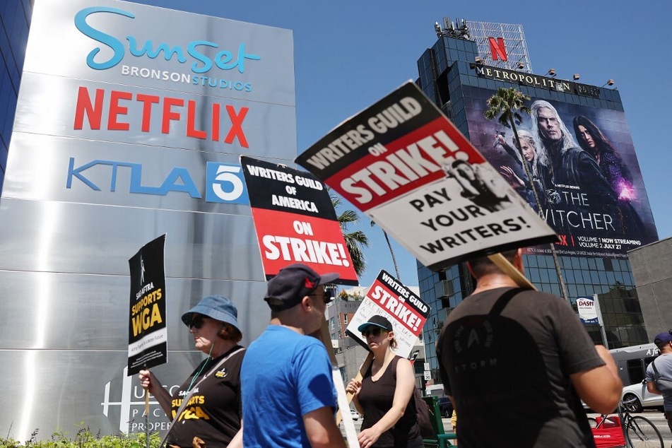 People carry signs as SAG-AFTRA members walk the picket line in solidarity with striking WGA workers outside Netflix offices on July 11, 2023, in Los Angeles, California.