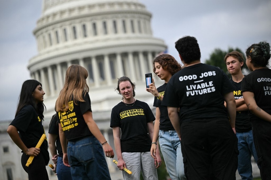 Sunrise Movement members who protested at House Speaker Kevin McCarthy's office stand on the East Lawn at the US Capitol in Washington DC.