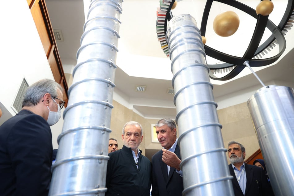 A handout picture provided by the Iranian presidency shows President Masoud Pezeshkian (C-L) and the Atomic Energy Organization of Iran (AEOI) chief Mohammad Eslami (C-R) during the National Day of Nuclear Technology in Tehran, on April 9, 2025.