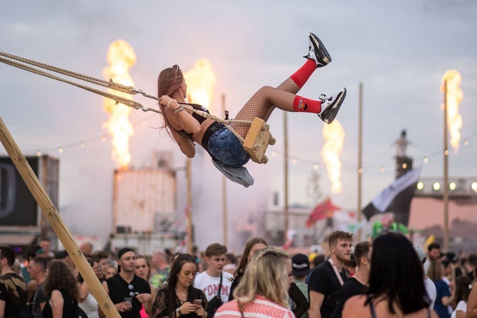 Eine Frau schaukelt auf dem Festivalgelände, das wie eine eigene Stadt konzipiert ist. (Archivbild)