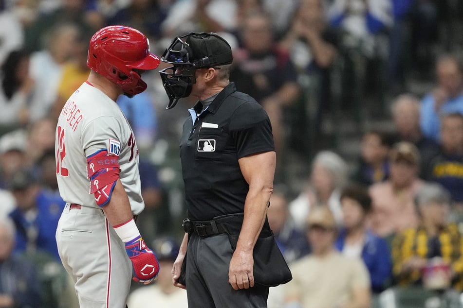 Kyle Schwarber #12 of the Philadelphia Phillies (l.) argues with home plate umpire Jim Wolf #28 (r.) after striking out against the Milwaukee Brewers in the first inning at American Family Field on September 3, 2025 in Milwaukee, Wisconsin.