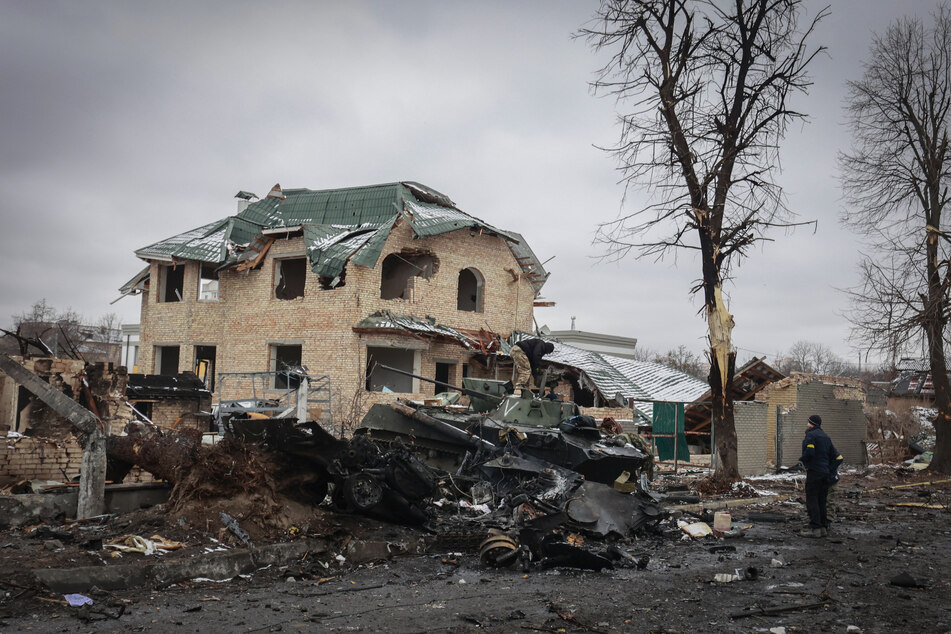 Ein Einwohner aus dem ukrainischen Butscha blickt auf die ausgebrannten Überreste russischer Militärfahrzeuge.