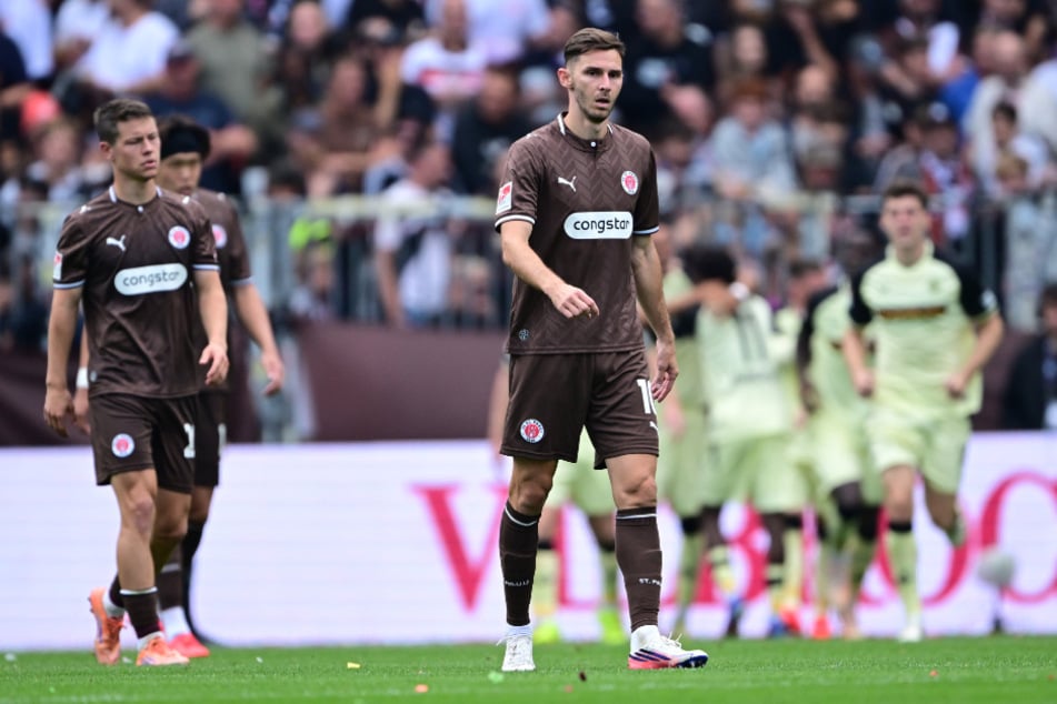 Betretene Gesichter bei den St.-Pauli-Profis, während Kaiserslautern im Hintergrund über den Führungstreffer jubelt.