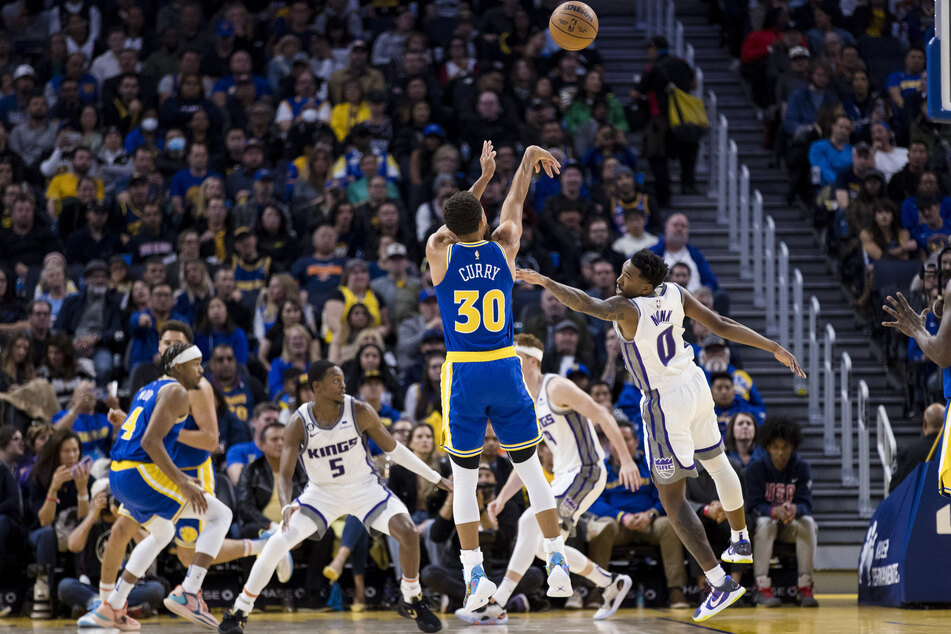 Golden State Warriors guard Stephen Curry takes a three-point shot over Sacramento Kings guard Malik Monk during the first half at Chase Center.