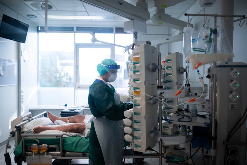 Eine Mitarbeiterin der Pflege in Schutzausrüstung betreut einen Corona-Patienten.