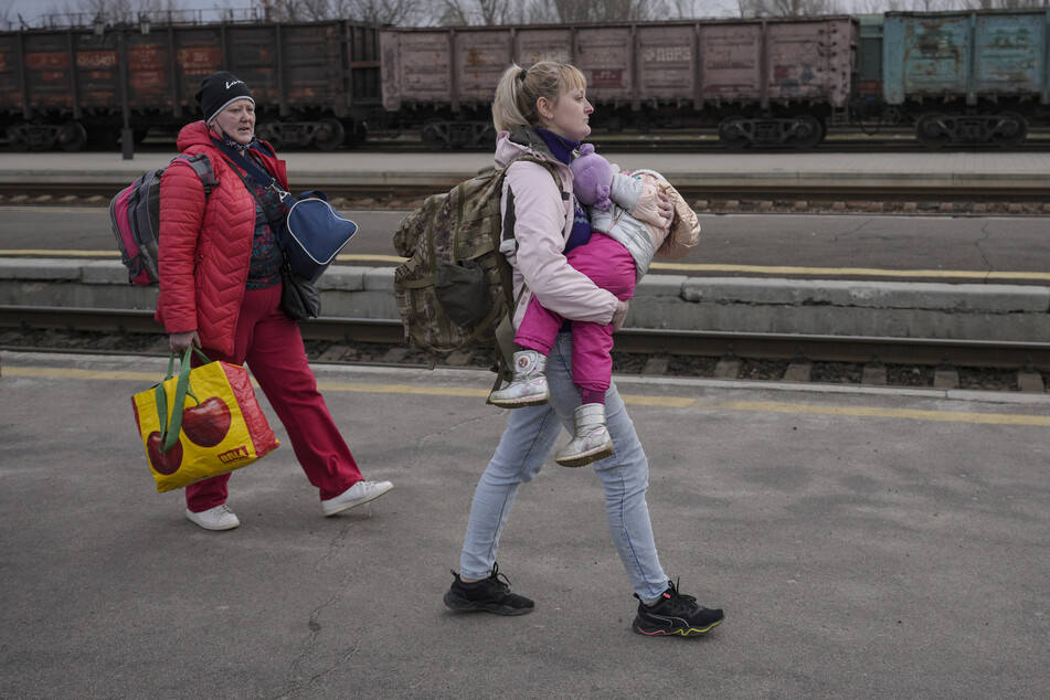 Eine Frau geht mit ihrem Kind im Arm einen Bahnsteig in Kostiantyniwka in der Region Donezk in der Ostukraine entlang, um einen Zug nach Kiew zu nehmen.