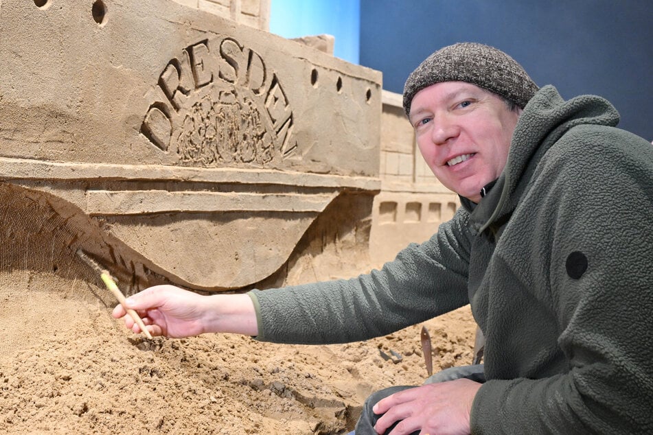 Sandkünstler Jeroen van de Vlag (56) schnitzt die letzten Wellen und das Schaufelrad des Dampfers aus dem Sand.