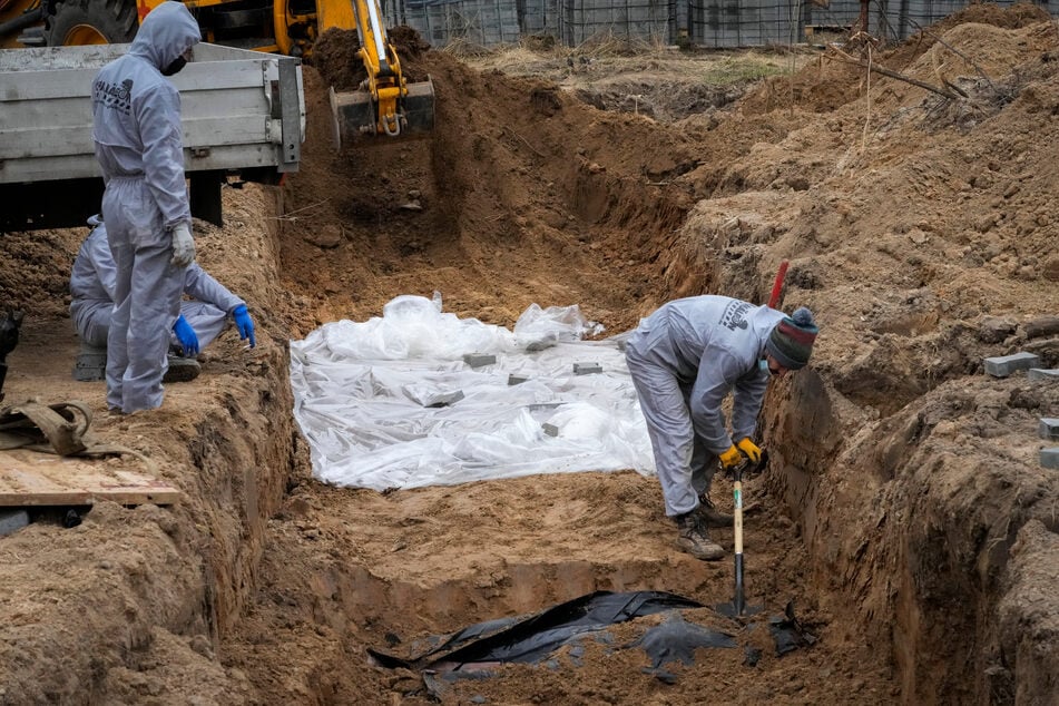 Butscha: Männer in Schutzkleidung exhumieren Leichen von Zivilisten, die während der russischen Besatzung getötet wurden.