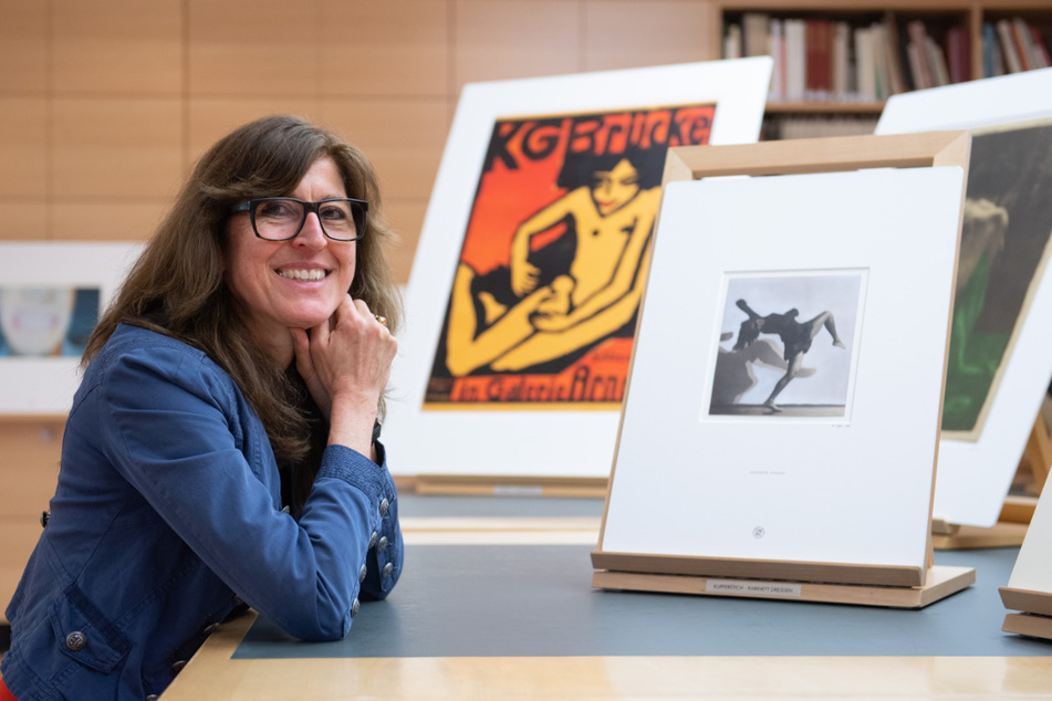Stephanie Buck, Direktorin des Kupferstich-Kabinetts in Dresden, sitzt im Studiensaal vor dem Kunstwerk "Gret Palucca mit doppeltem Schatten" von Charlotte Rudolph. Dahinter: Ein Plakat der Ausstellung der Künstlergemeinschaft "Brücke" von Ernst Ludwig Kirchner.