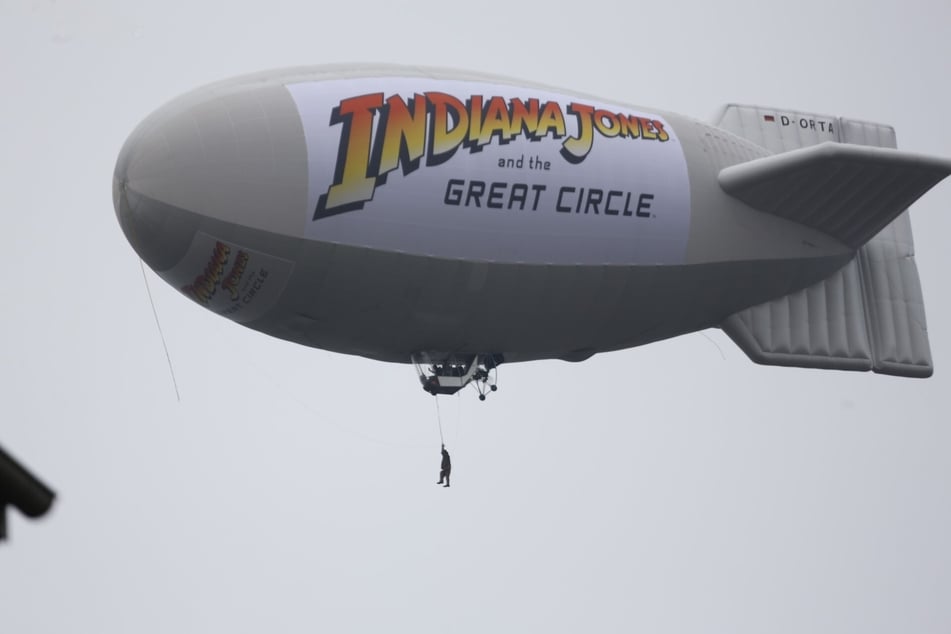 So waghalsig erlebt man Indiana Jones normalerweise nur in Filmen: Zu Werbezwecken hat ein Videospiel-Entwickler kurzerhand eine Puppe an einen Zeppelin gehängt und über Köln fliegen lassen.