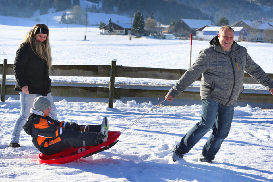 Alexander Merz (r.) und seine Frau Gisela Merz spielen mit ihrem 10-jährigen Pflegekind Alois im Schnee.