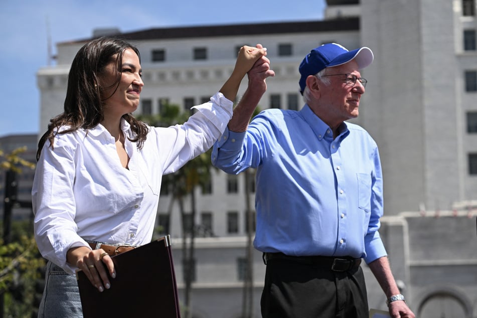 Senator Bernie Sanders (r.) and Representative Alexandria Ocasio Cortez hold hands as they arrive for a Fighting Oligarchy rally in Los Angeles on April 12, 2025.