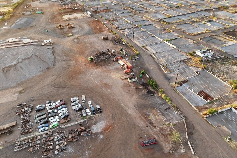 An aerial view of destroyed and damaged cars next to lots which have been cleared of fire debris, covered in gray gravel, on August 4, 2024, in Lahaina, Hawaii.