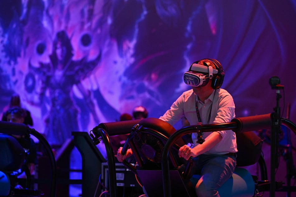 A visitor wears a virtual reality (VR) headset as he plays the World of Warcraft: The War Within online game of Blizzard Entertainment during the media day at the Gamescom video games trade fair in Cologne, western Germany on August 21, 2024.