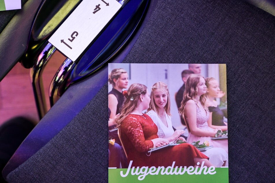 Ein Prospekt zur Jugendweihe liegt auf einem Festsaal-Stuhl kurz vor der Feierstunde. Die Jugendweihe hat besonders in Ostdeutschland eine stark verwurzelte Tradition.