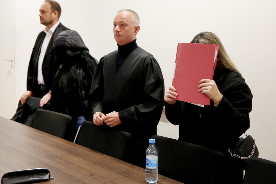 Die beiden angeklagten Tagesmütter (2.v.l. und r.) warten mit ihren Anwälten Andre Wallmüller (2.v.r.) und Christian Beckmann (l.) im Gerichtssaal auf den Beginn des Prozesses wegen fahrlässiger Tötung.