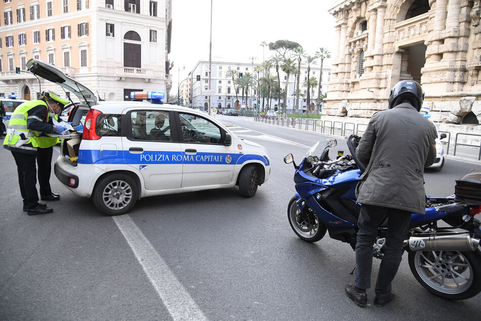 Polizisten überprüfen während der Ausgangssperre wegen der Corona-Pandemie einen Motorradfahrer.