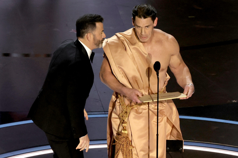 John Cena (r.) later adopted a makeshift toga to finish presenting the award.