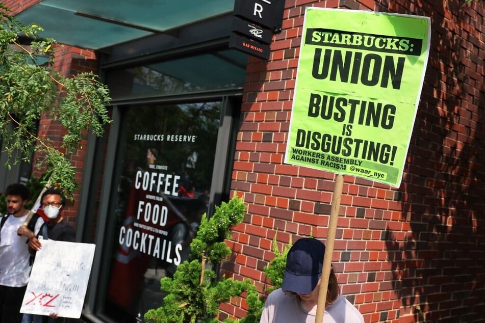 Starbucks workers and supporters raise a "Union Busting is Disgusting!" sign outside a cafe in New York City.