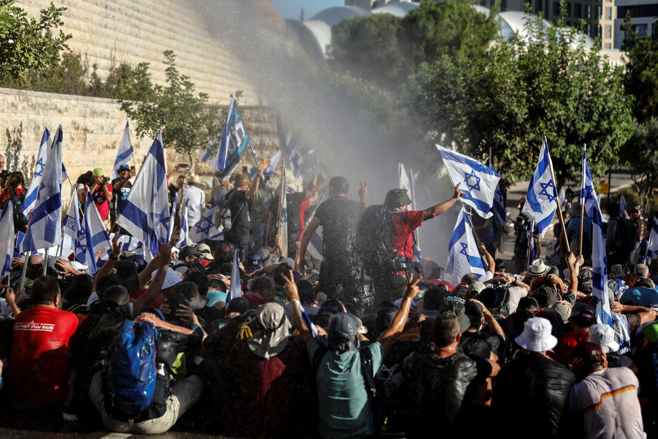 A water cannon sprays water to remove protesters from a road leading to the Knesset during a demonstration against Israeli Prime Minister Benjamin Netanyahu and his nationalist coalition government's judicial overhaul.