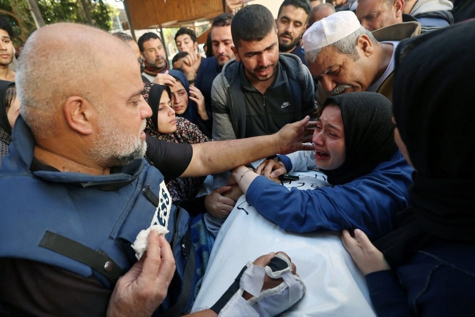 The wife (r.) of Hamza Wael Dahdouh, a journalist with the Al Jazeera television network, and his father, Al Jazeera's bureau chief in Gaza, Wael Al-Dahdouh (l.), mourn over his body during his funeral.