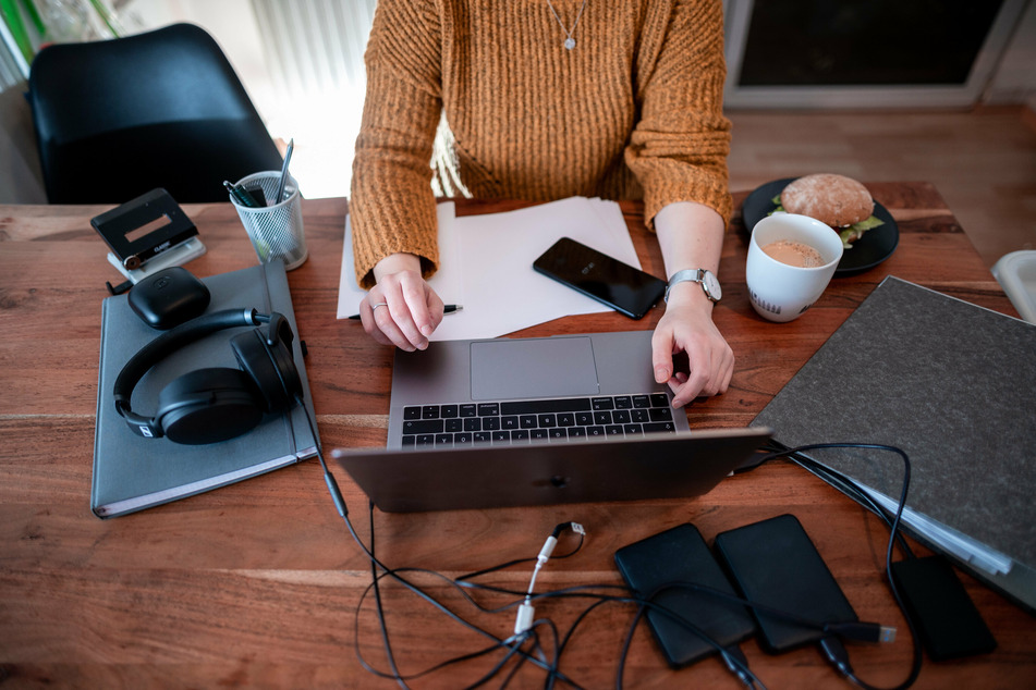 Eine Frau sitzt mit einem Laptop an einem Tisch im Homeoffice.