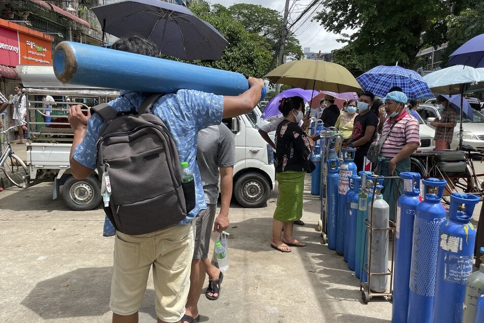 Menschen mit ihren Sauerstoffflaschen vor einer Nachfüllstation in Yangon, einer Stadt in Myanmar.