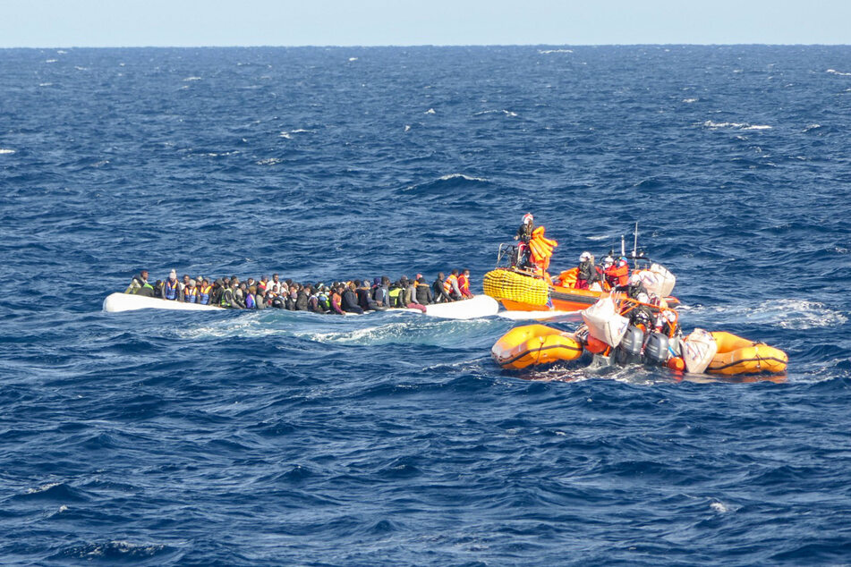 Rund 120 Geflüchtete aus Libyen sitzen in einem Schlauchboot. Helfer des Seenotrettungsschiffs "Ocean Viking" nähern sich mit weiteren Booten.