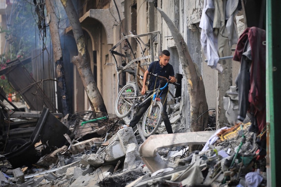 A Palestinian boy carries his bicycle as he climbs over debris a day after an operation by the Israeli Special Forces in the Nuseirat refugee camp in the central Gaza Strip.