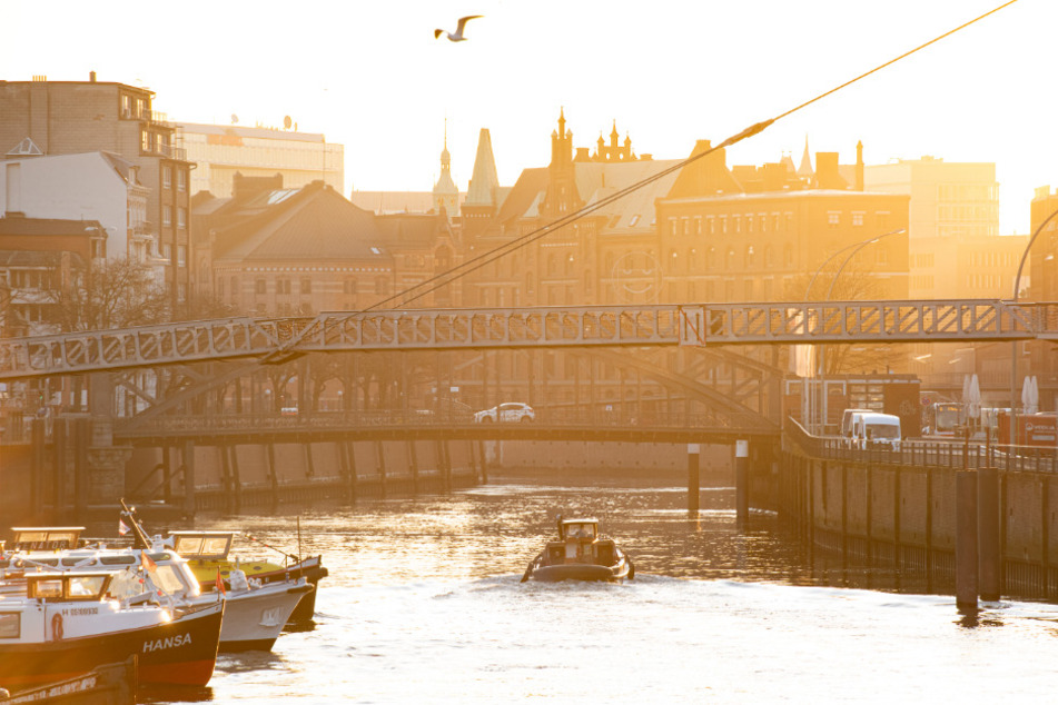 Ein Schiff fährt während des Sonnenaufgangs über den Binnenhafen in Richtung Speicherstadt.