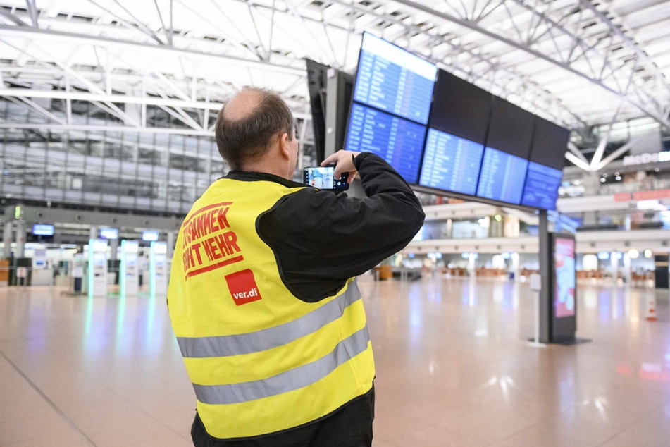 Ein Flughafen-Mitarbeiter steht im menschenleeren Terminal am Hamburger Airport.