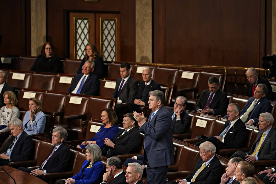 Conservative Democratic Senator Joe Manchin applauding Biden's speech from the Republican side of the aisle, where he sat for the evening.