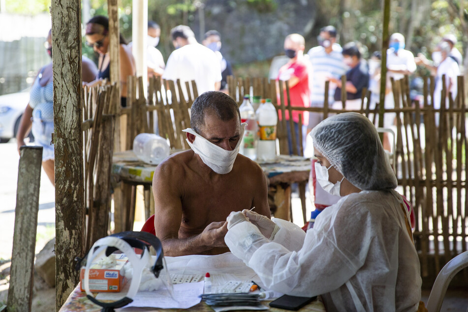 Ein Mann mit Mundschutz und nacktem Oberkörper unterzieht sich einem Covid-19-Schnelltest am Stadtrand von Rio De Janeiro.