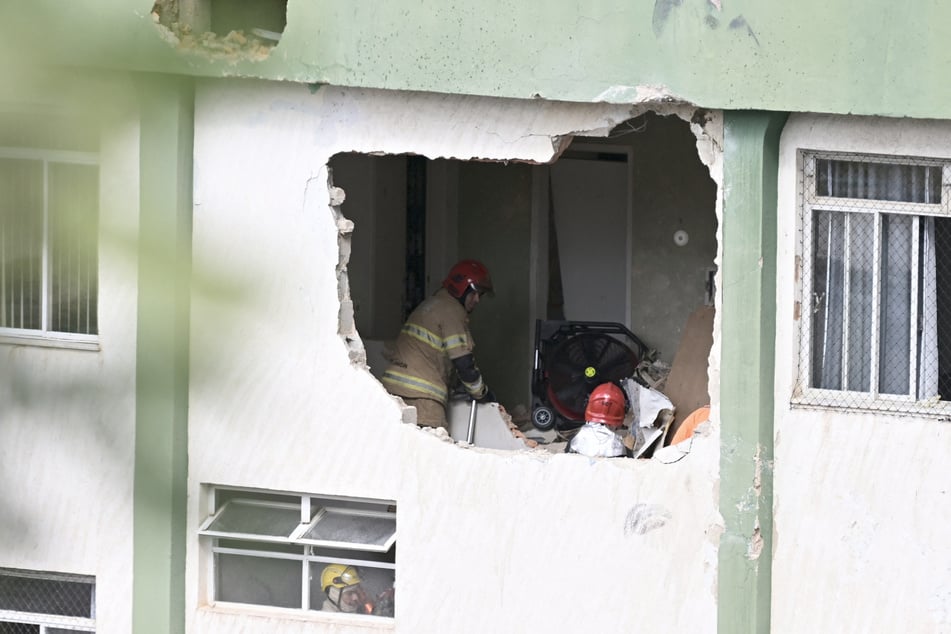 Feuerwehrleute nahmen das Stockwerk des Gebäudes unter die Lupe, in das der Flieger gekracht war.
