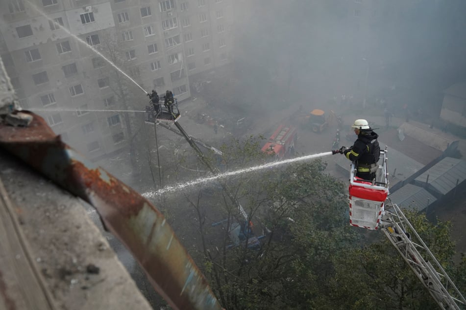 Feuerwehrleute löschen Gebäude nach einem russischen Bombenangriff in Charkiw.