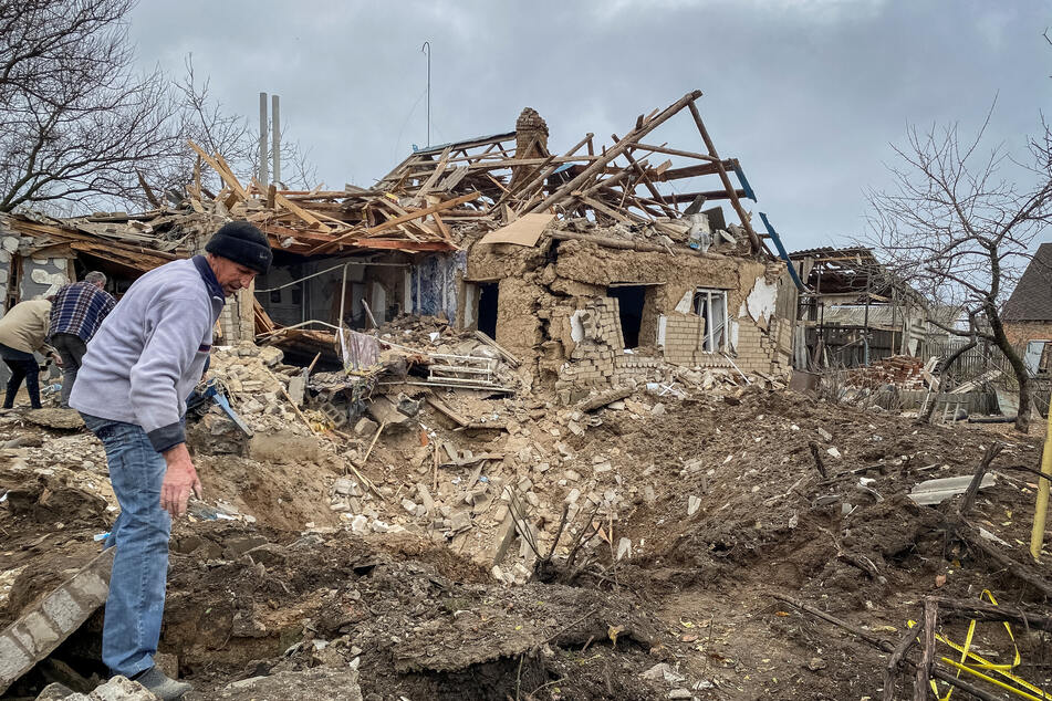 Local residents inspect a crater left by a Russian military strike in the village of Komyshuvakha, Zaporizhzhia.