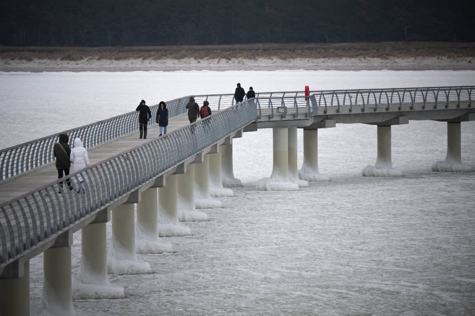Auch bei eisigen Temperaturen schlendern Besucher über die Seebrücke Prerow, die vollständig von Eis eingeschlossen ist.
