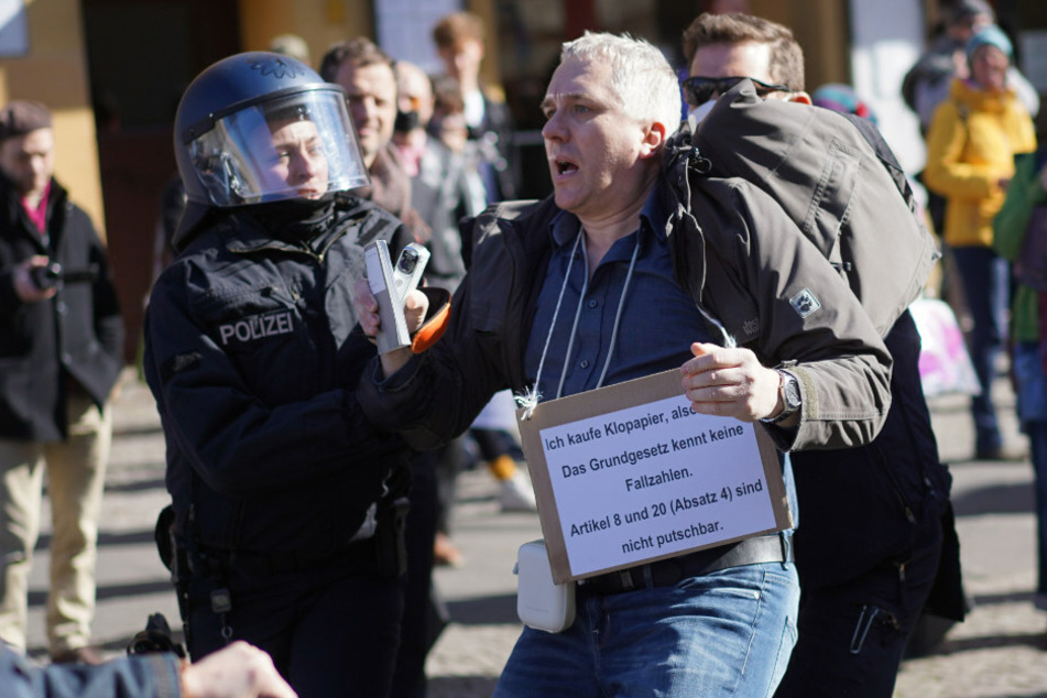 Ein Demonstrationsteilnehmer wird bei einer Demonstration unter dem Motto "Grundrechte verteidigen - Sage NEIN zur Diktatur!" auf dem Rosa-Luxemburg-Platz von Polizisten abgeführt.