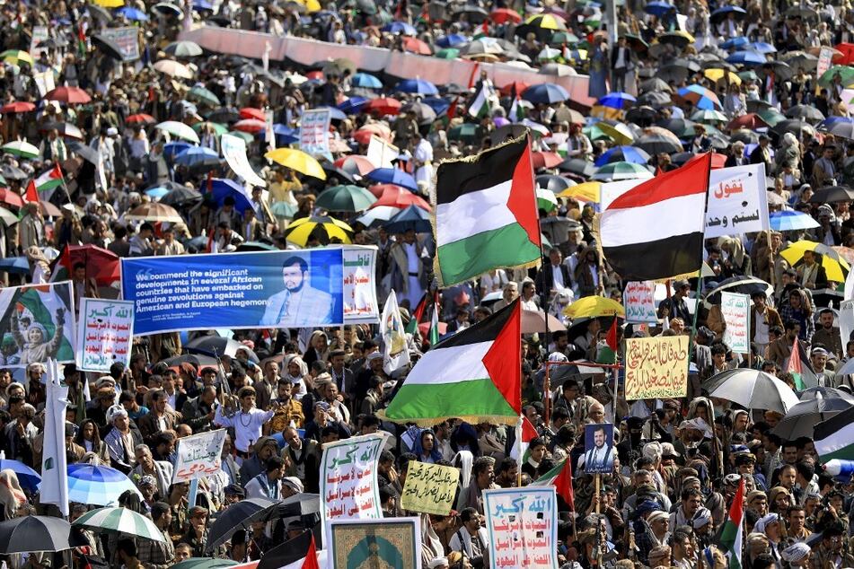 Yemenis lift signs and wave Palestinian flags as they march in the capital Sanaa in solidarity with the people of Gaza.