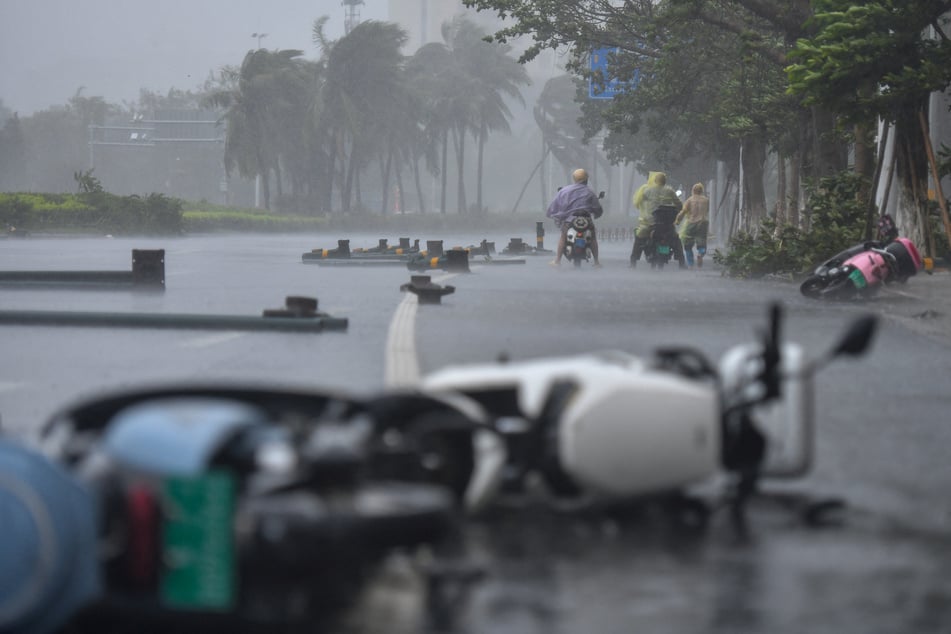 People ride electric scooters amid strong winds and heavy rainfall brought by Typhoon Matmo, in Haikou, Hainan province, China, on October 5, 2025.