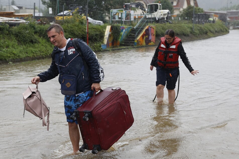 Touristen in Österreich waten, nachdem sie ihr Unterkünfte verlassen mussten, durch das Hochwasser.