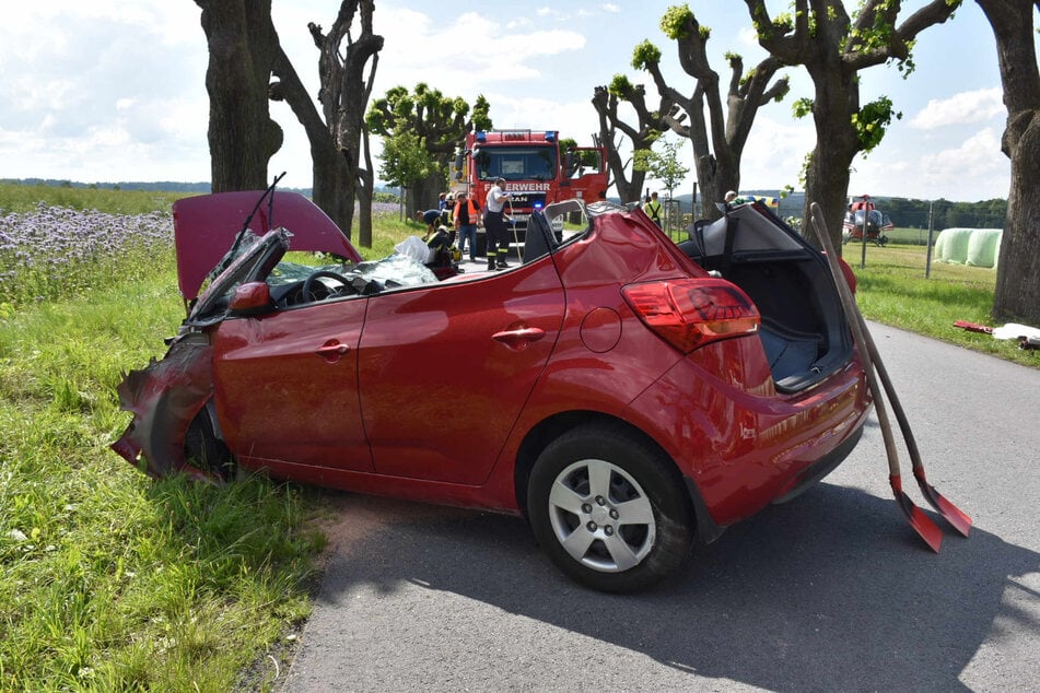 Der Feuerwehrwagen steht vor dem demolierten Wagen. Im Hintergrund (rechts) ist der Rettungshubschrauber zu sehen.